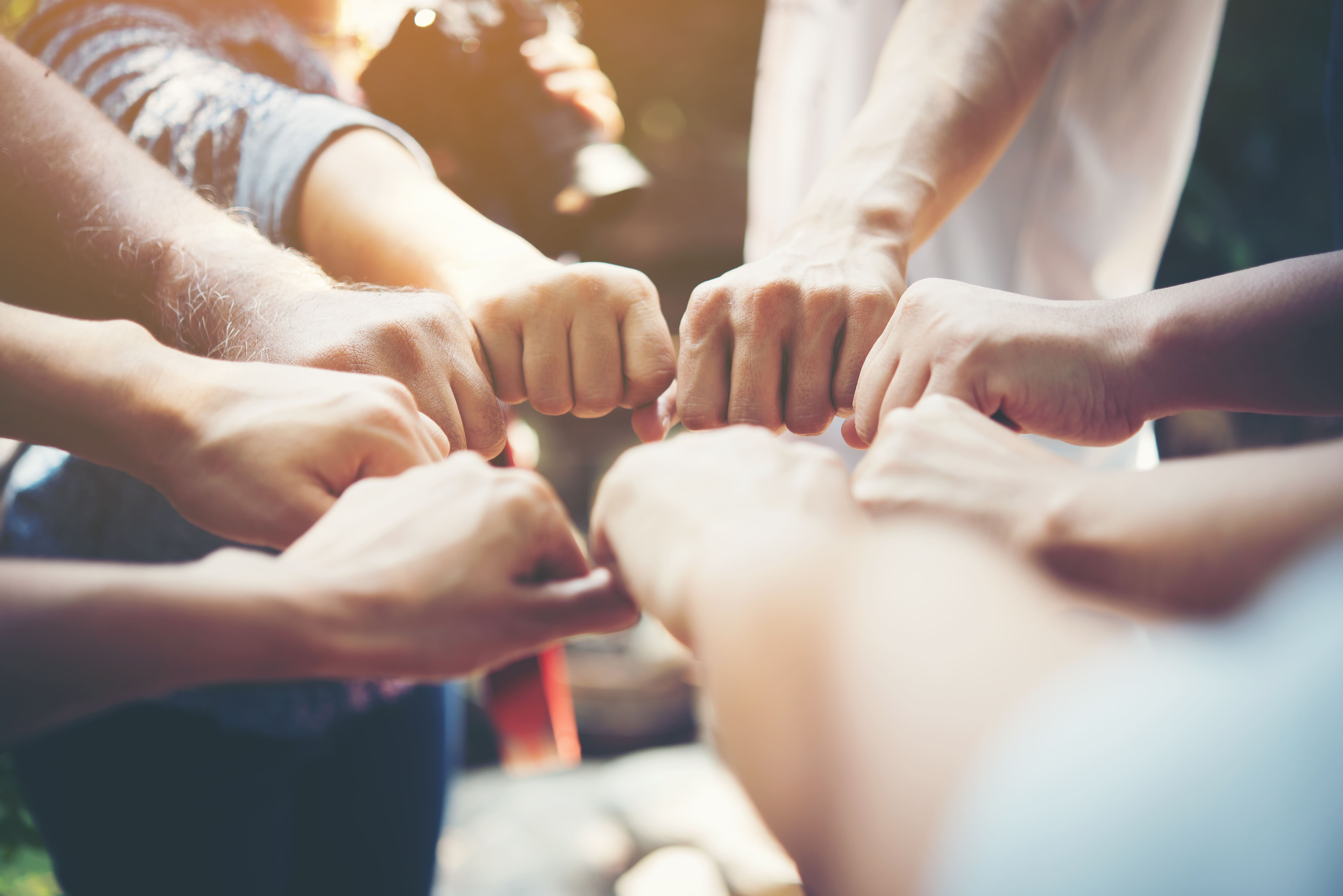 Equipe motivada com mãos cerradas ao centro do grupo